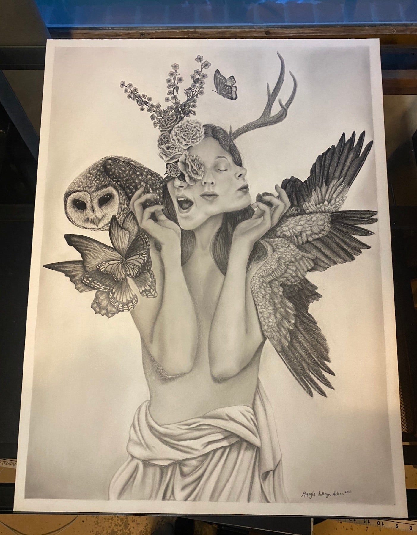Graphite drawing of a winged figure with an owl, antlers and butterflies